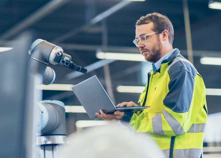functies werktuigbouwkunde engineer met laptop bij een robotarm